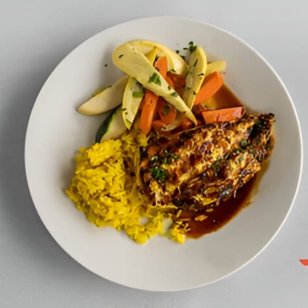 Lighthouse Bistro's baked chicken with yellow rice, carrots, and squash on a white plate.
