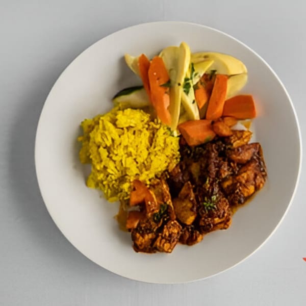 Lighthouse Bistro's global cuisine dish with yellow rice, roasted vegetables, and braised meat.