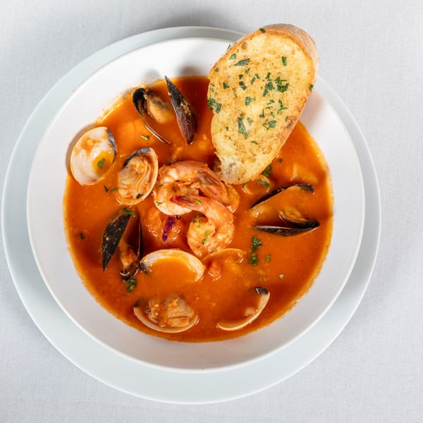 Lighthouse Bistro's seafood cioppino with shrimp, mussels, clams, and garlic bread in a white bowl.
