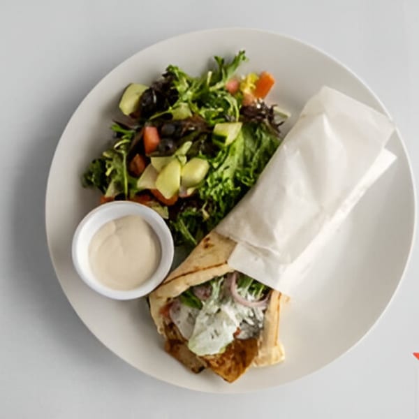 Lighthouse Bistro's gyro wrap with a side salad and dipping sauce on a white plate.